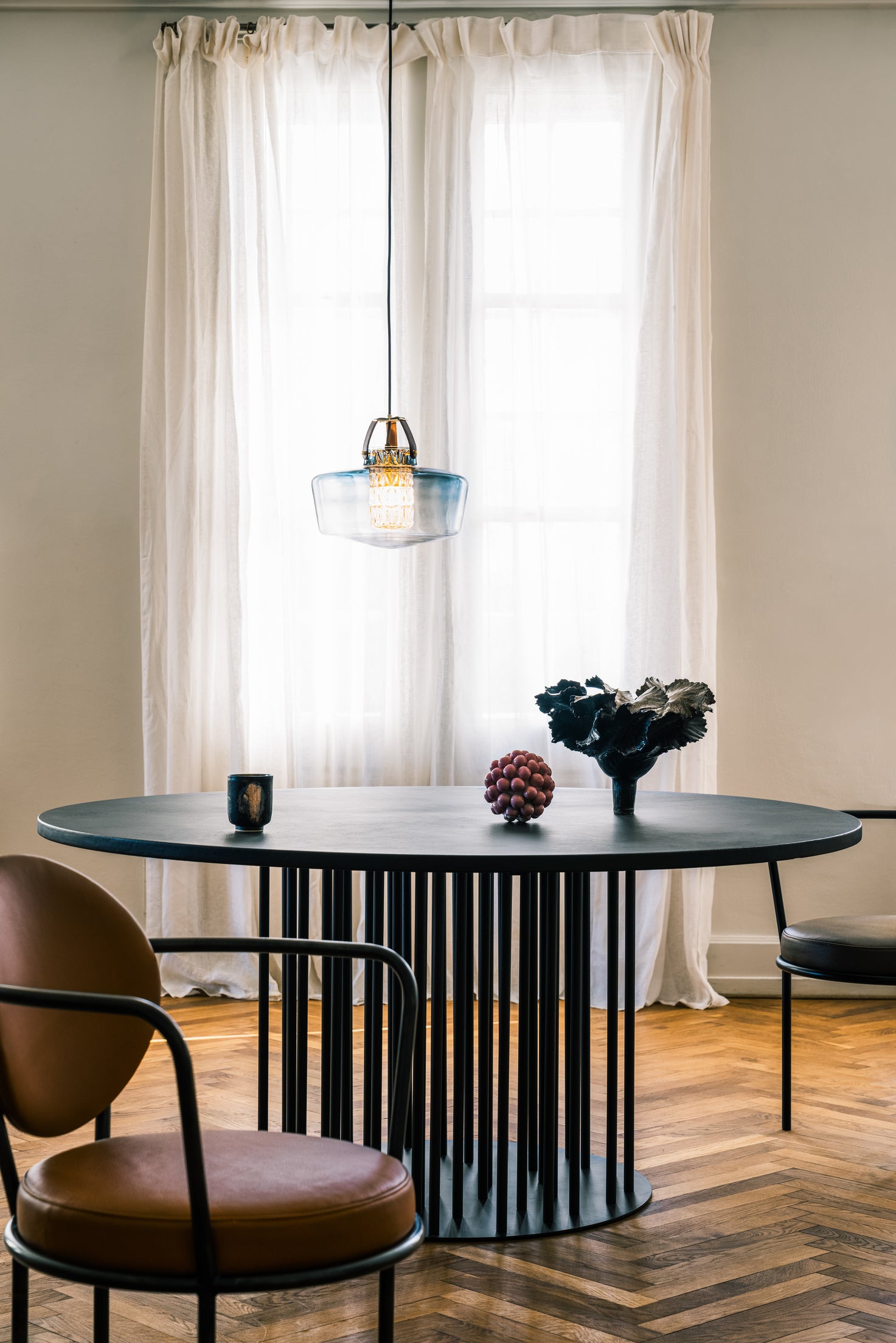 Lampen har en røgfarvet glasskærm i mundblæst glas, et facetslebet cylinderrør samt unikke detaljer i bl.a. læder.