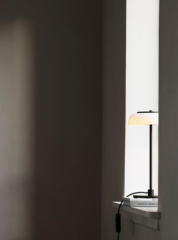 Bordlampe med sort stel og fatning og glasskærm i opalglas, i vindueskarm