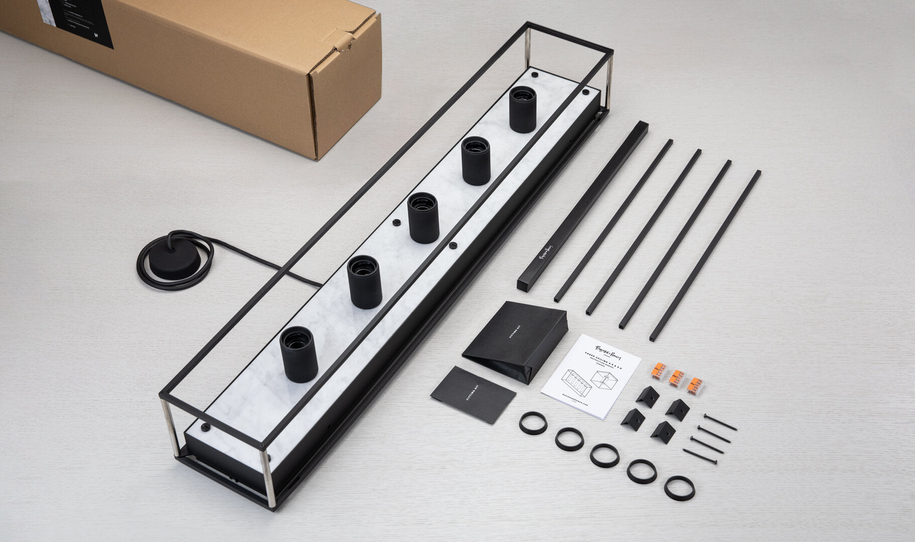 Caged loftlampe med fem pære fra Buster and Punch i sort med bagpanel i hvid marmor.