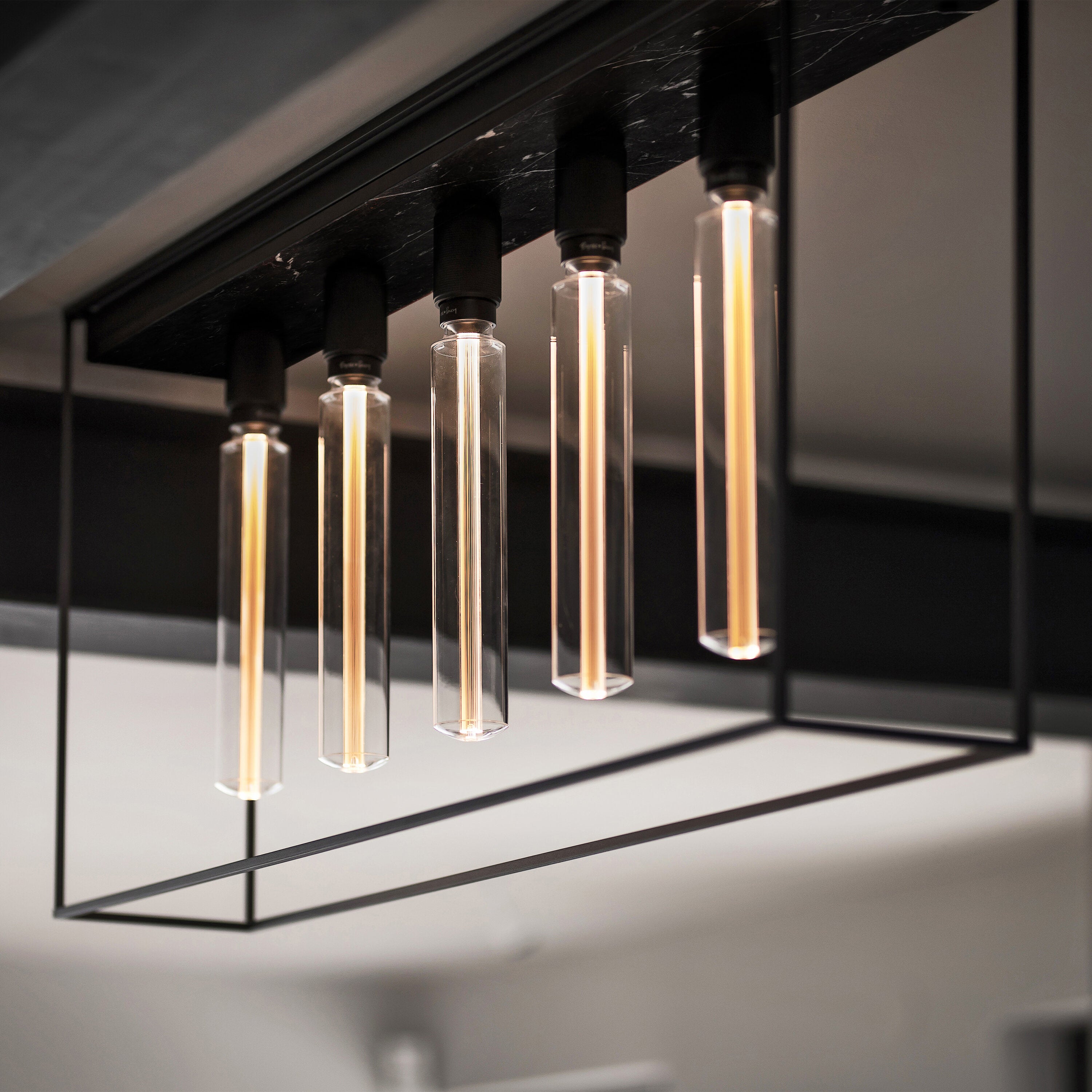 Caged loftlampe med fem pære fra Buster and Punch i sort med bagpanel i sort marmor.