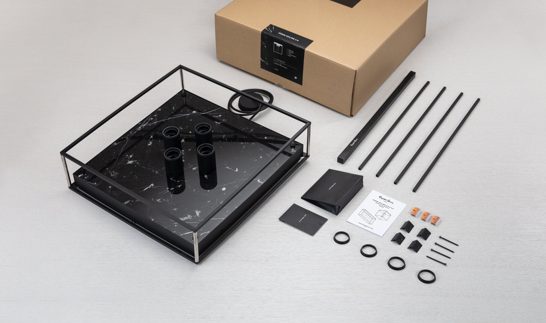 Caged loftlampe fra Buster and Punch i sort med hvid marmor bagplade.