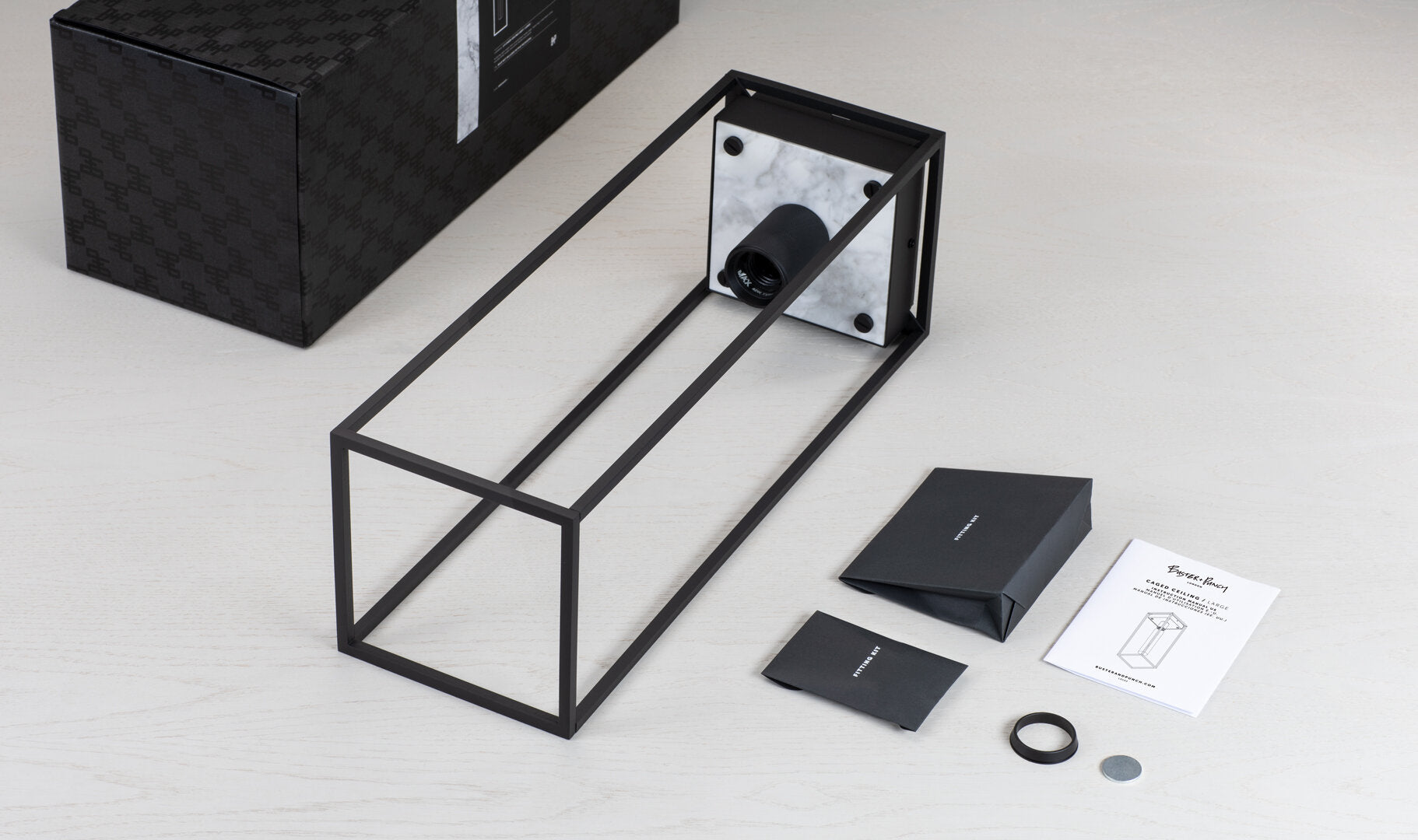 Caged loftlampe fra Buster and Punch i sort med bagpanel i hvid marmor.