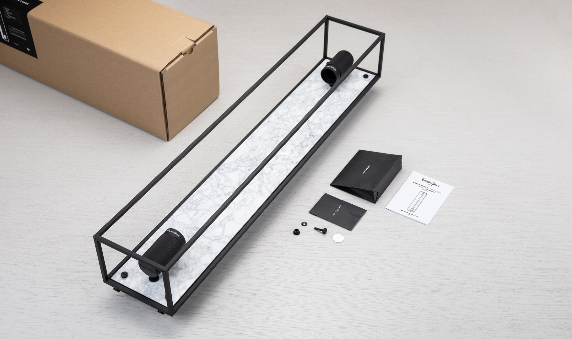 Buster and Punch caged wall lamp X-large i sort metal med bagplade i hvid marmor.