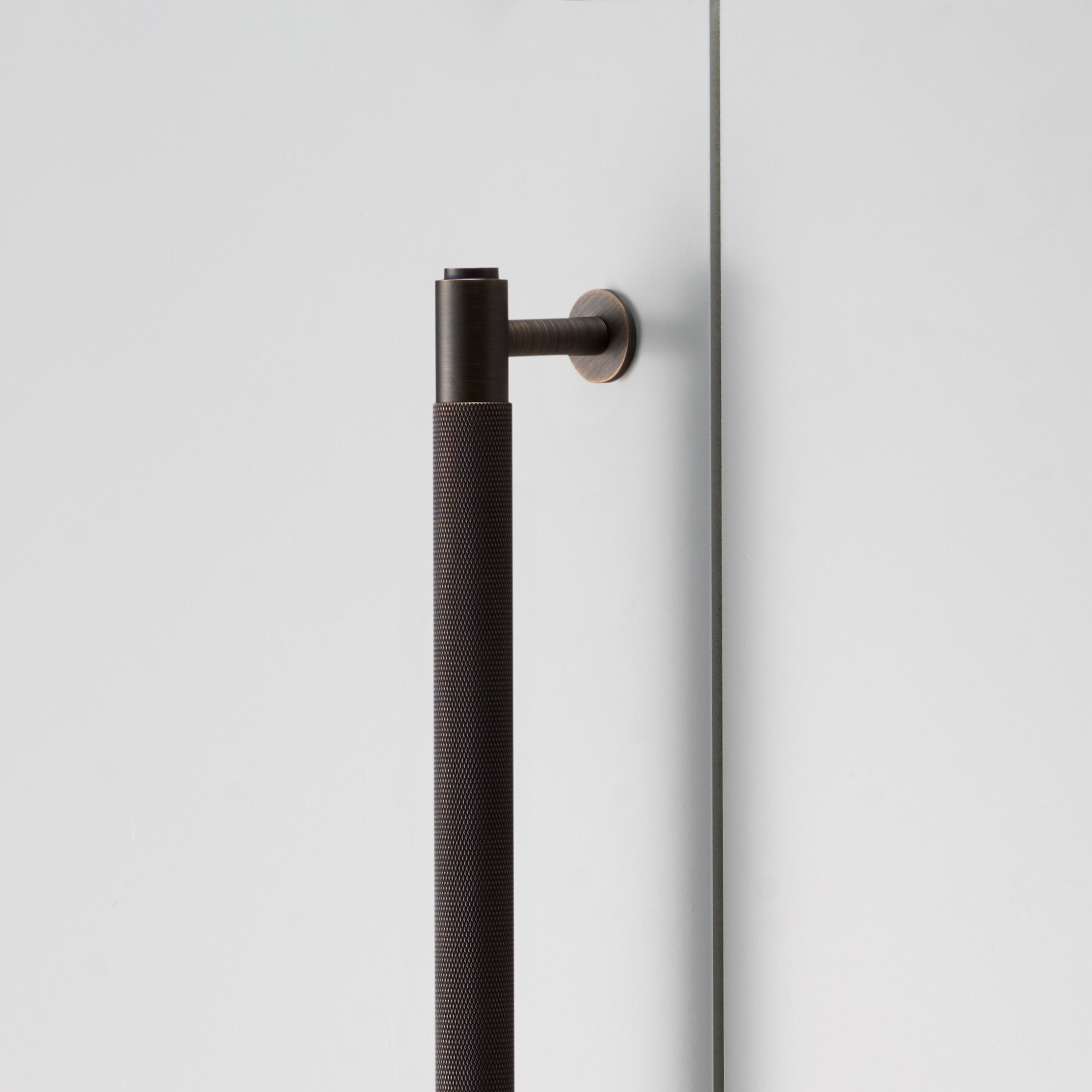 Langt skabsgreb i bruneret messing (Smoked bronze) med diamond cut mønster fra Buster + Punch