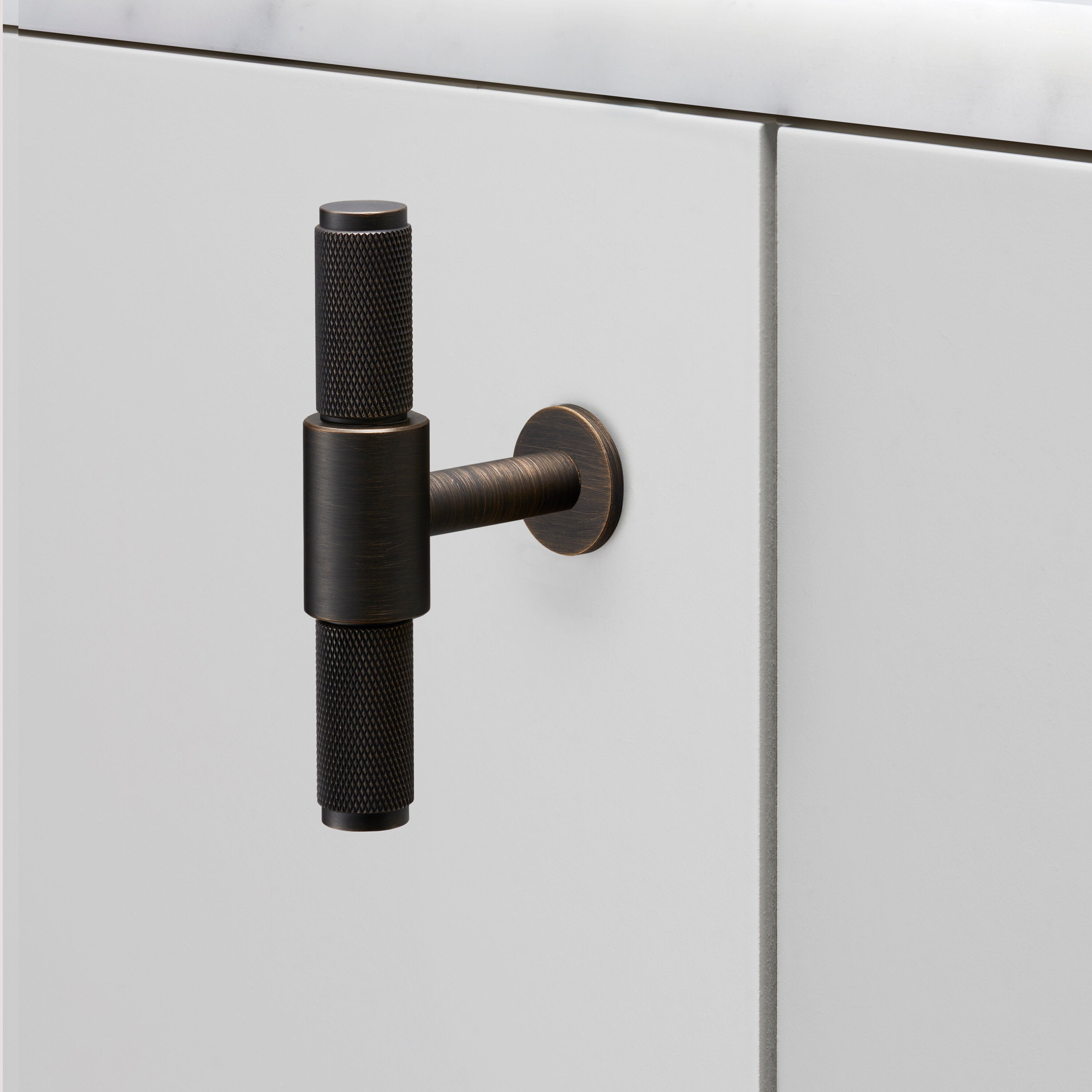 Eksklusiv T-bat knop fra Buster + Punch i bruneret messing (smoked bronze) med diamond cut mønster (cross).