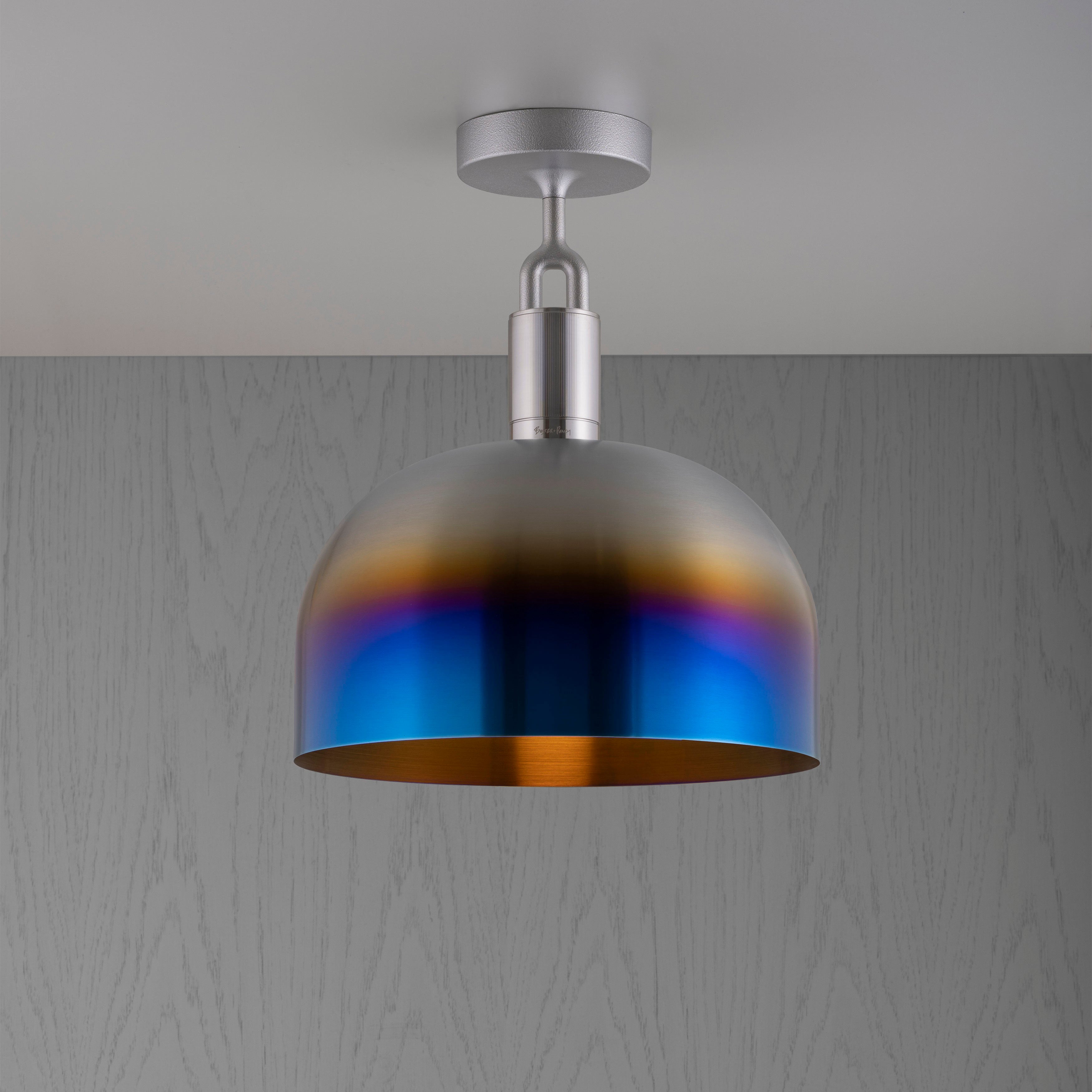 Loftlampe med fatning af stål og skærm af brændt stål, på grå baggrund.