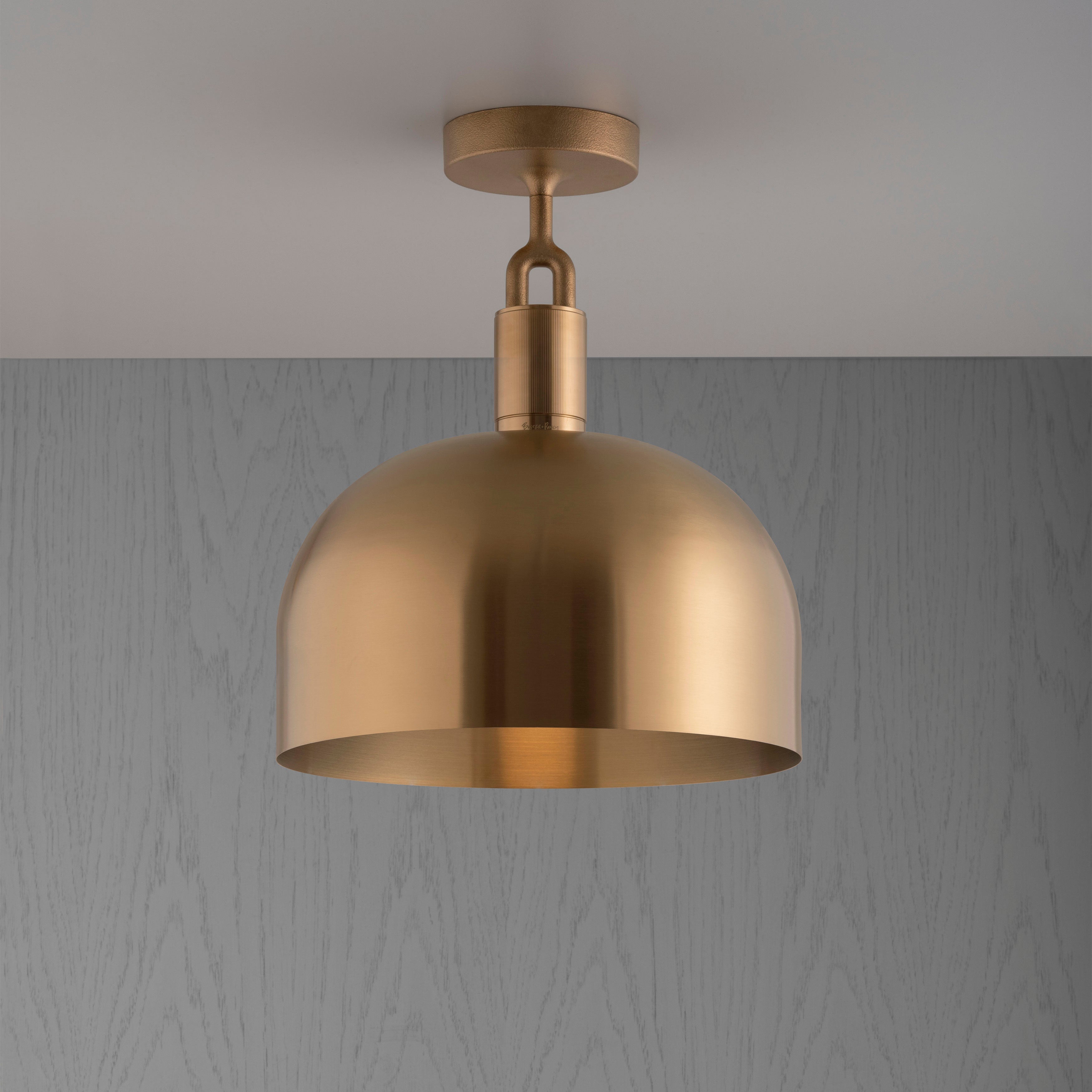 Loftlampe med skærm og fatning i messing, på grå baggrund.