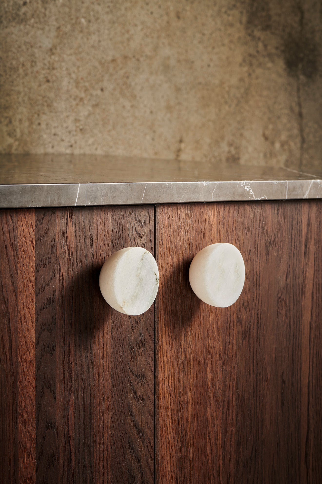 2 stk. runde og koniske møbelknopper i massiv hvid marmor.  Her ses knopperne monteret på mørke træfronter.