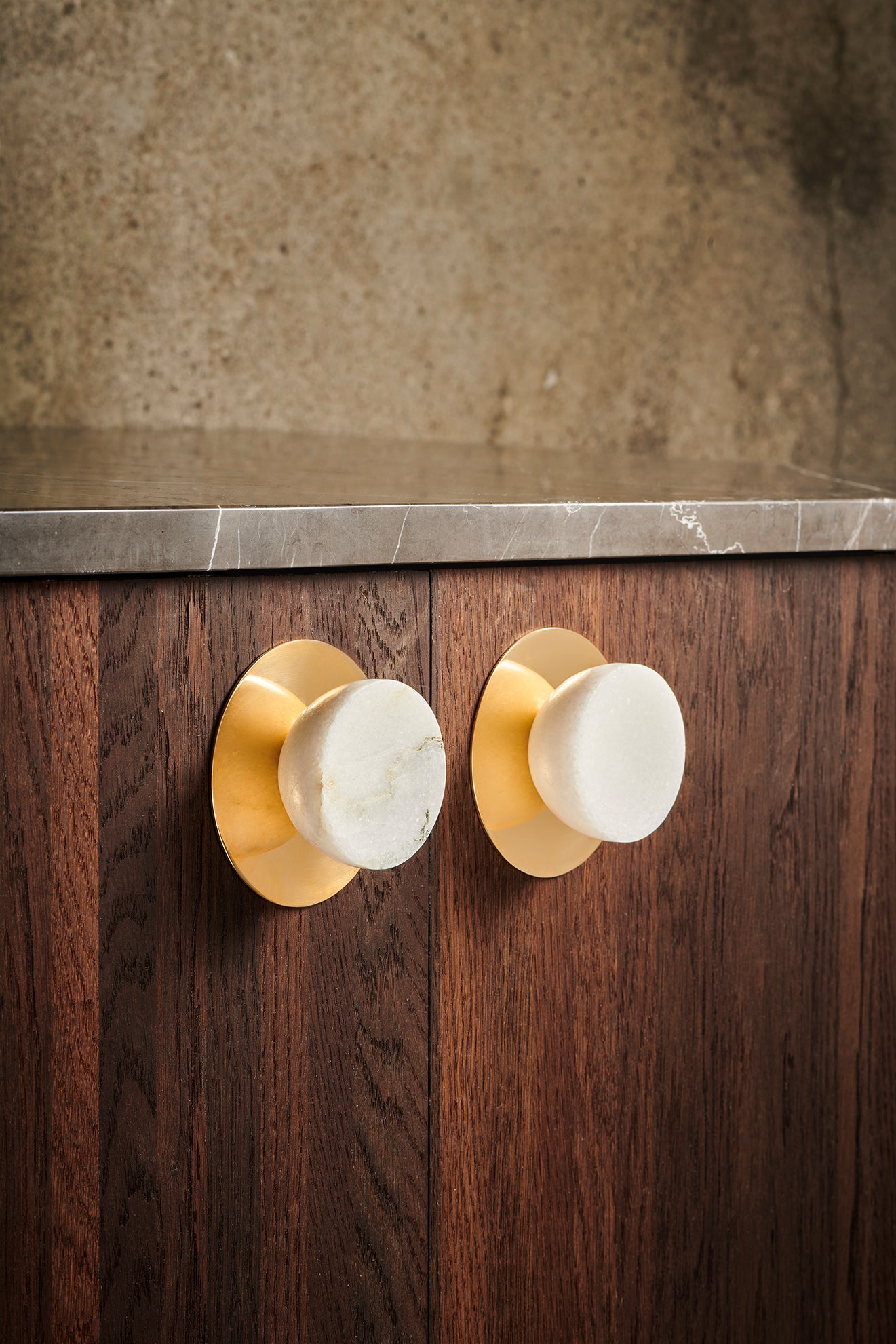 Her ses de to møbelknopper monteret på mørke fronter og med den runde messing bagplade, som kan tilkøbes til knopperne.