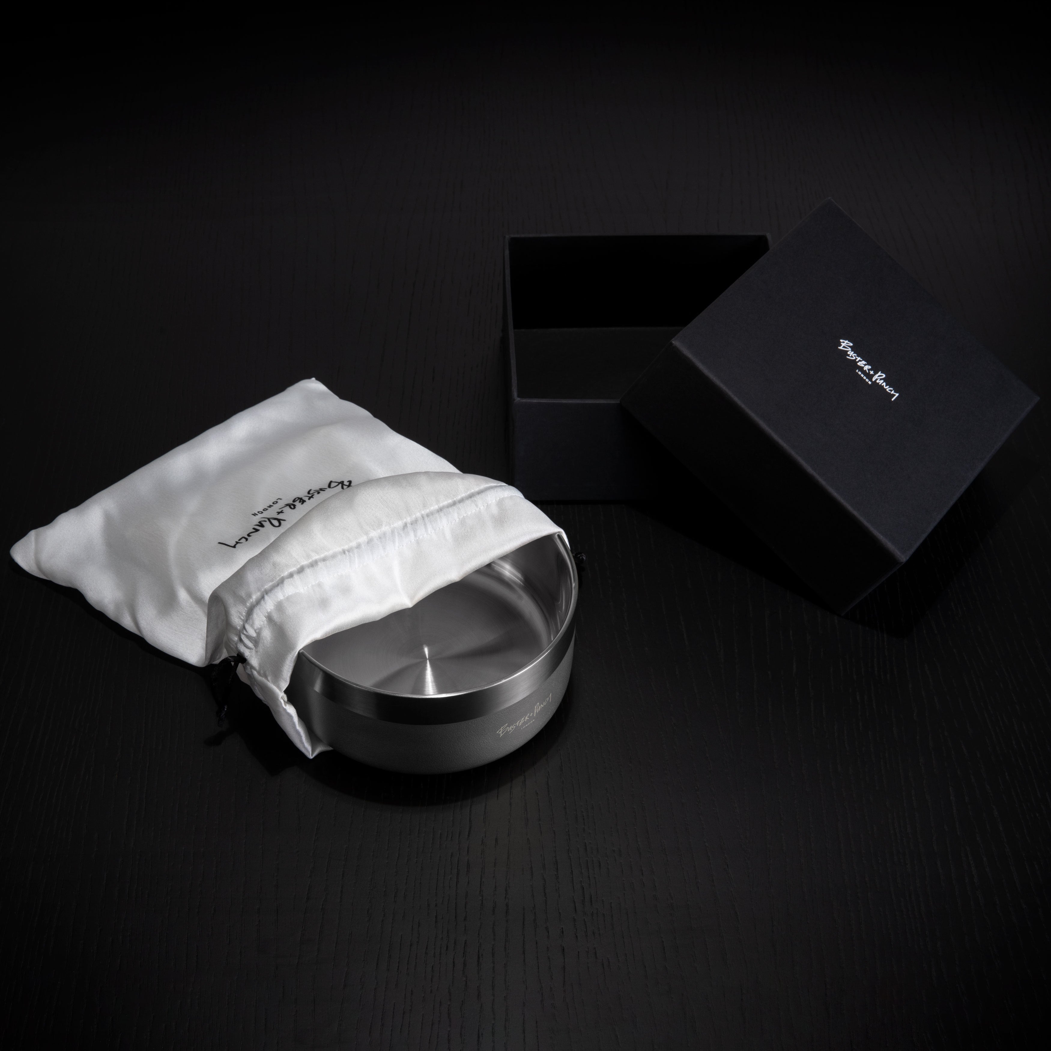 Æske indeholdende hundeskål i stål med gun metal finish, på sort træbord.