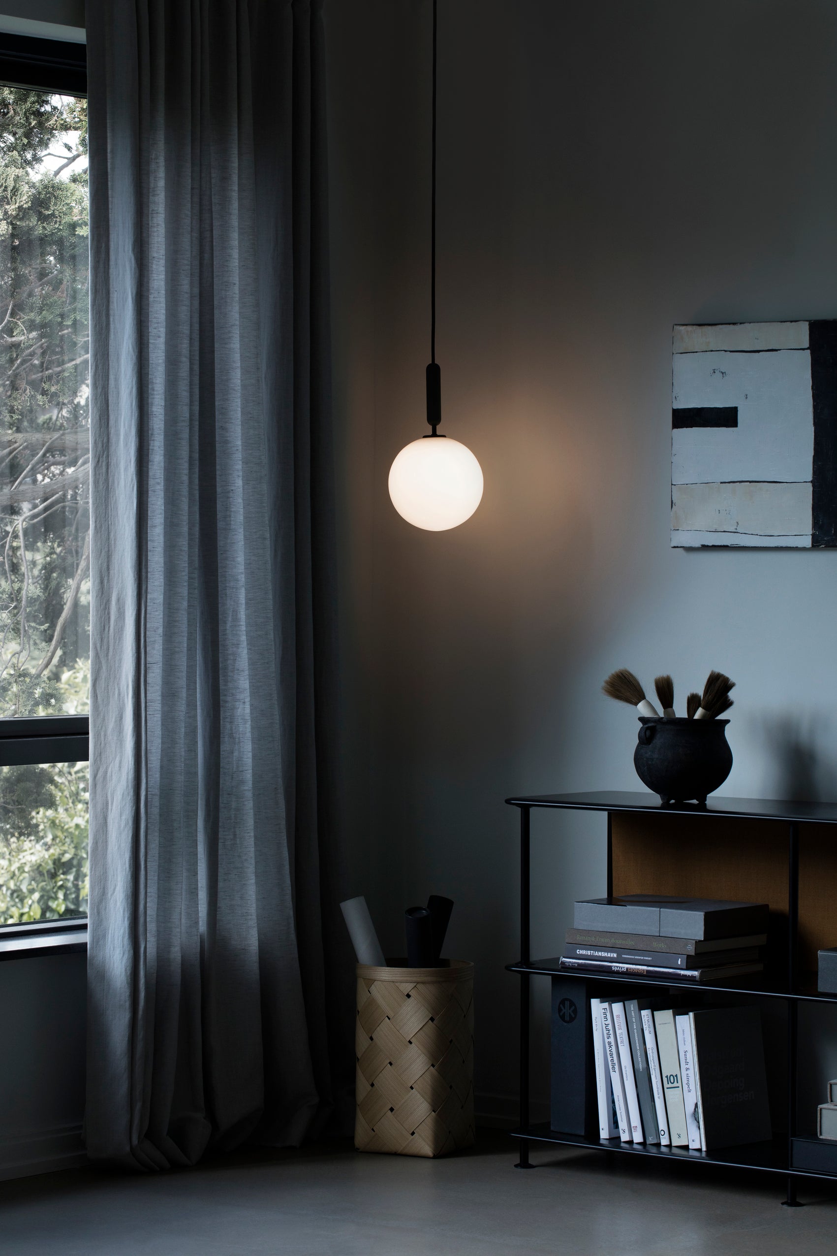 Pendel med rund skærm af opalglas og aflang grå fatning, i dagligstuemiljø
