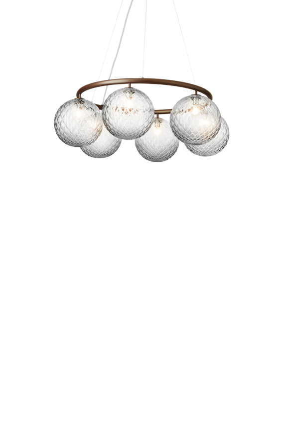 Lysekrone bestående af seks runde skærme i klart optikglas samt bruneret krone, på hvid baggrund