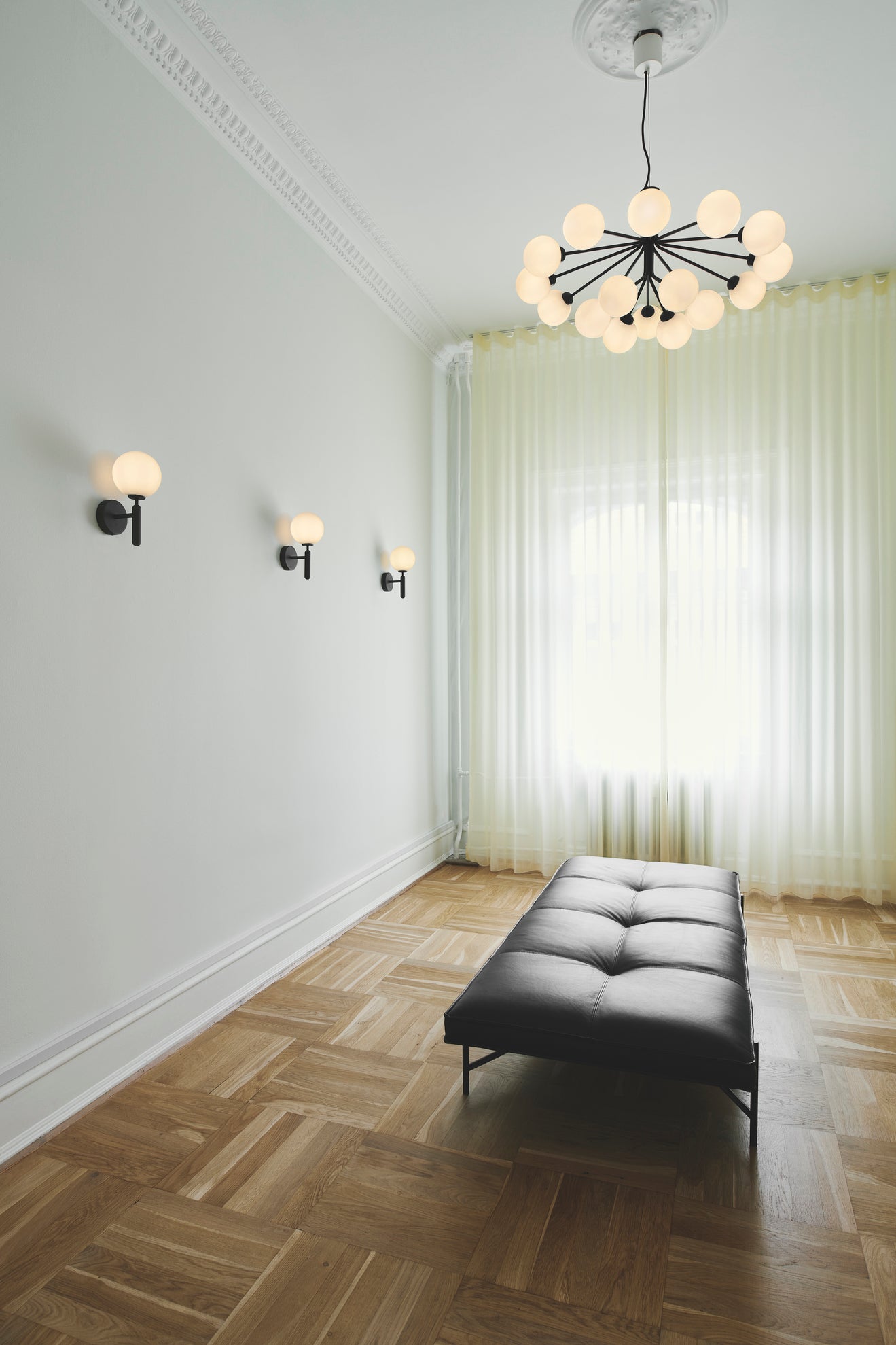 Lysekrone bestående af runde skærme i opalglas samt sort krone, i dagligstuemiljø