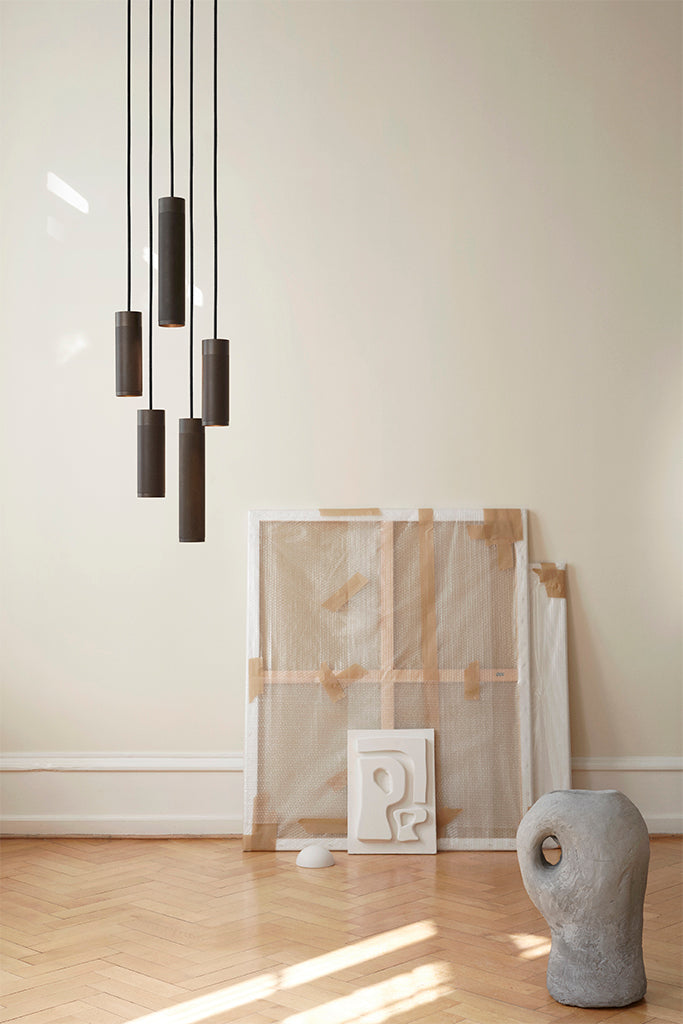 Stue med lofthængt lampe med fem pendler i massiv bruneret messing, sort stofledning og afdæmpet belysning