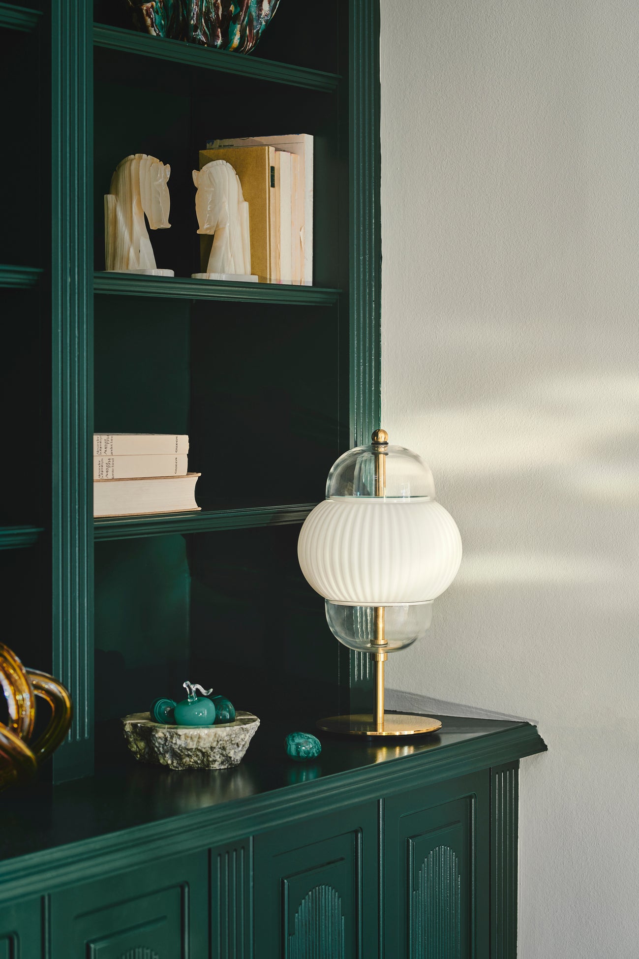 Bordlampe i klart glas og mat hvidplisseret glas. Derudover har lampen guldfarvede detaljer og fod.
