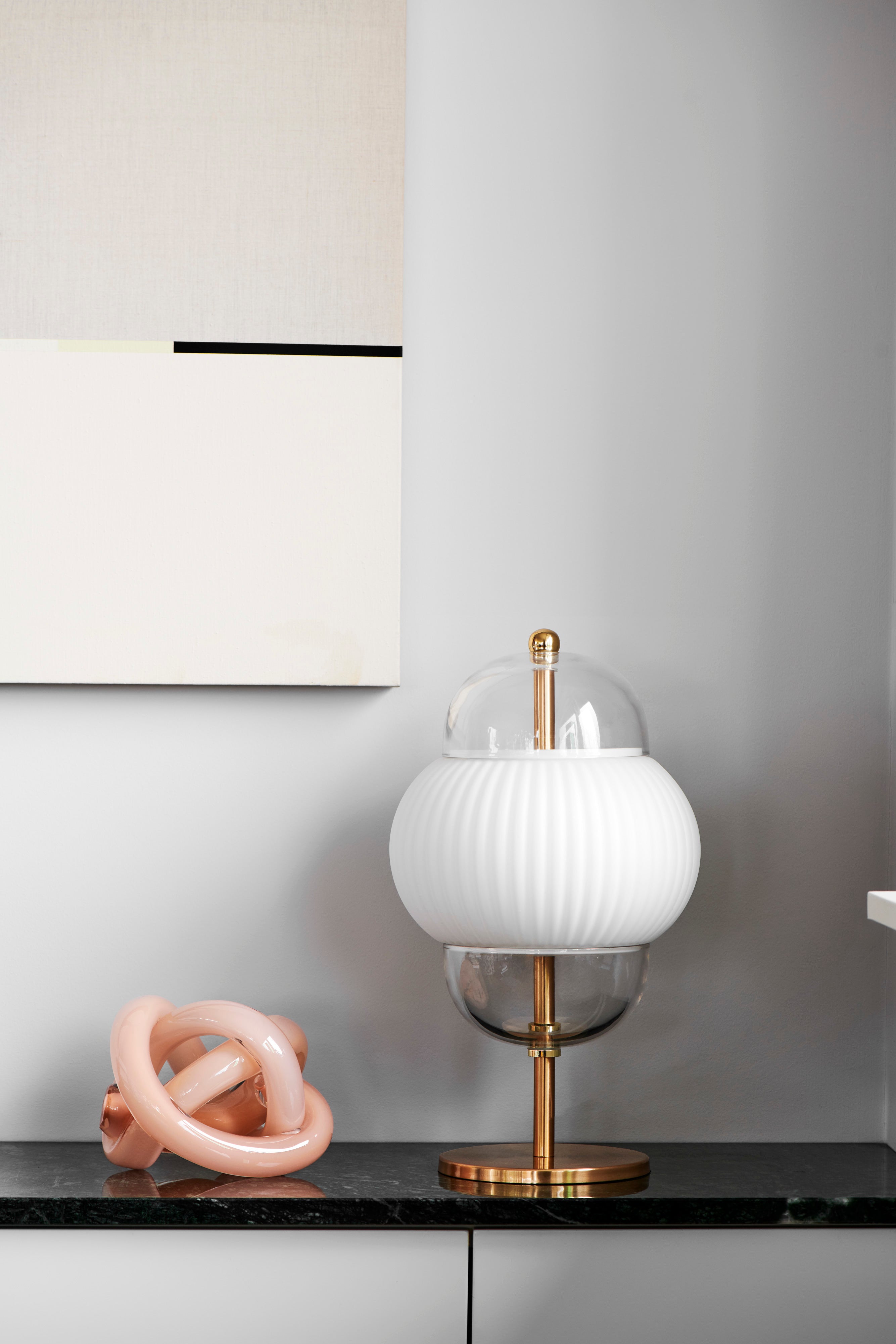 Bordlampe i klart glas og mat hvidplisseret glas. Derudover har lampen guldfarvede detaljer og fod.