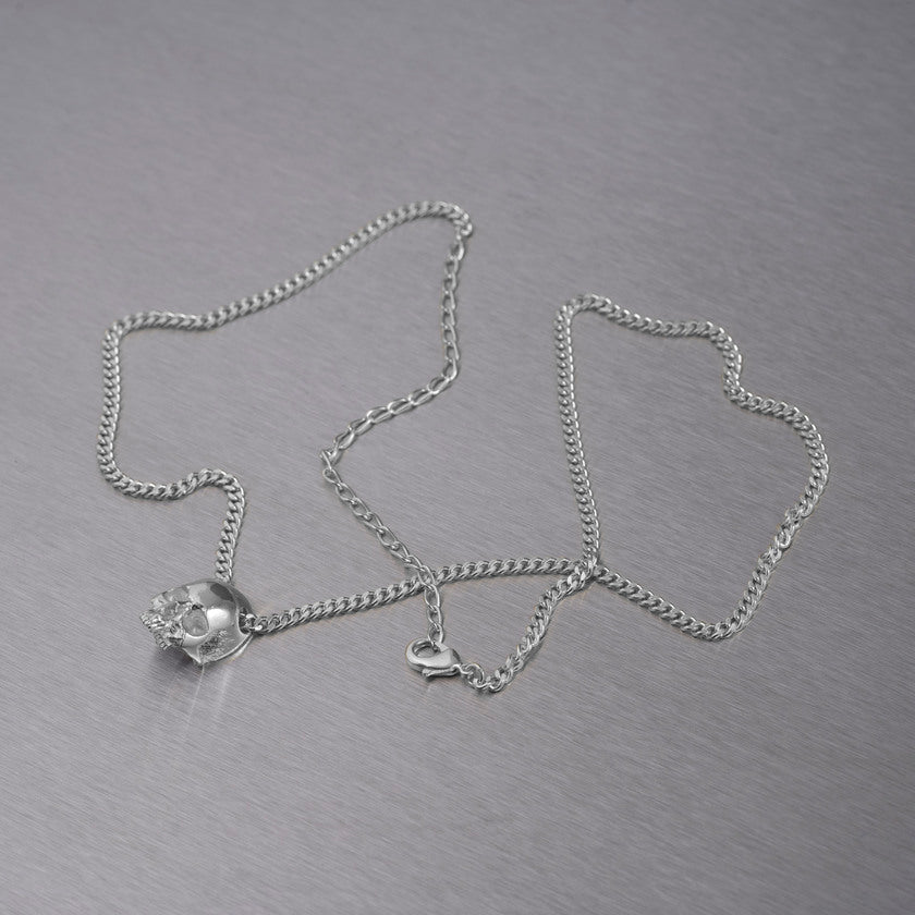 Halskæde med vedhæng i form af et dødningehoved, i sølv.