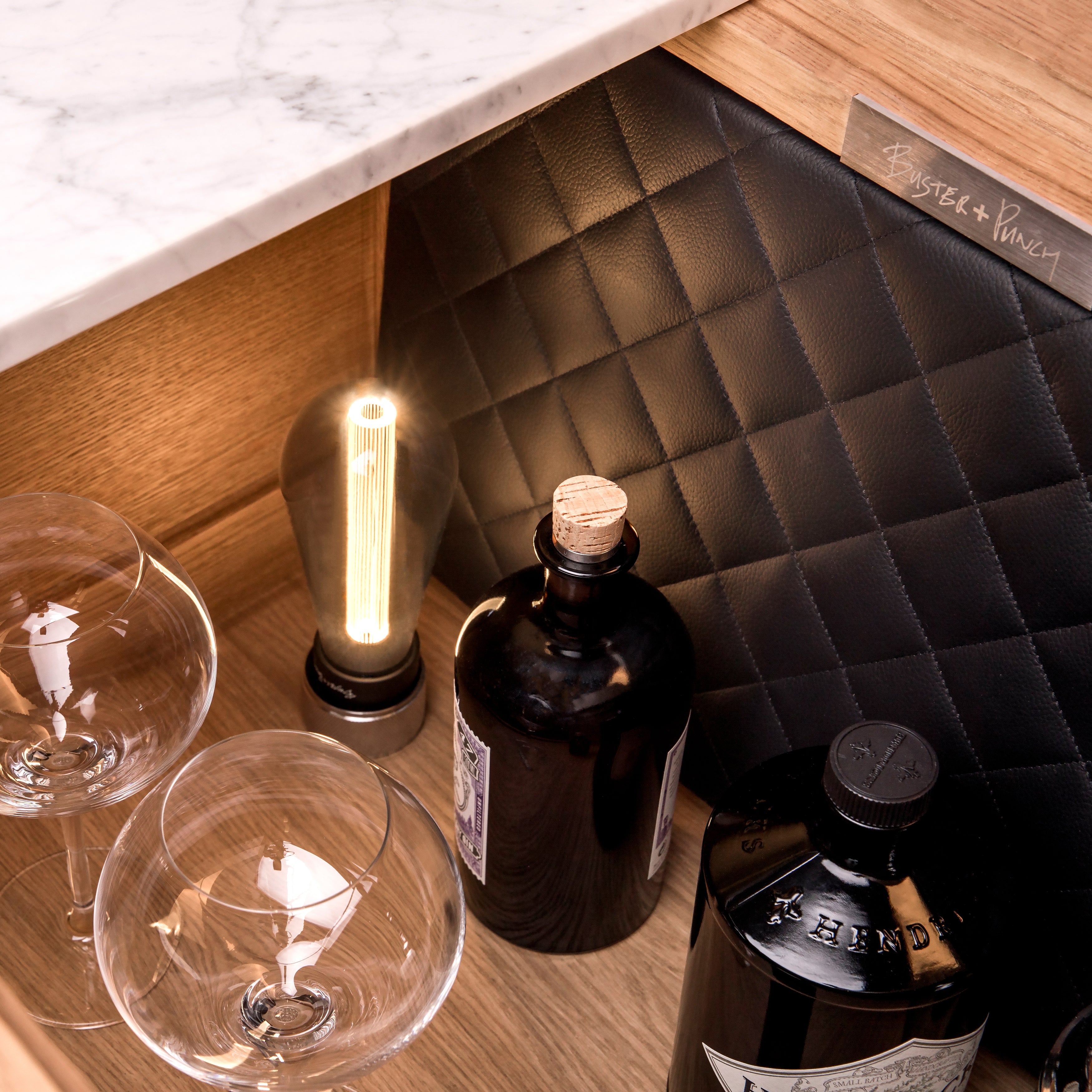 Bar i eg med høje ben, bordplade i hvidmarmor og integreret lyskilde.