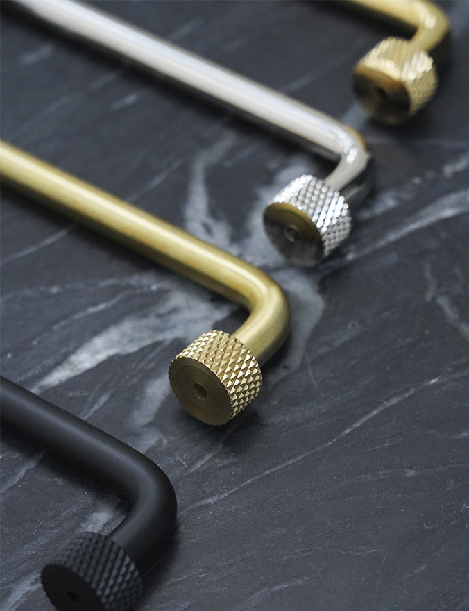 Køkkengreb i messing med en overflade i blank krom. Grebet har runde fødder med riflet diamond cut mønster, som matcher til quooker armatur.