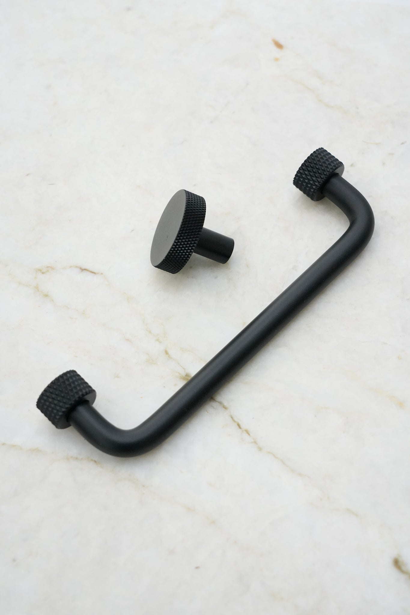 Køkkengreb i massiv messing med en mat sort overflade. Grebet har runde fødder med riflet diamond cut mønster, som matcher til quooker armatur.