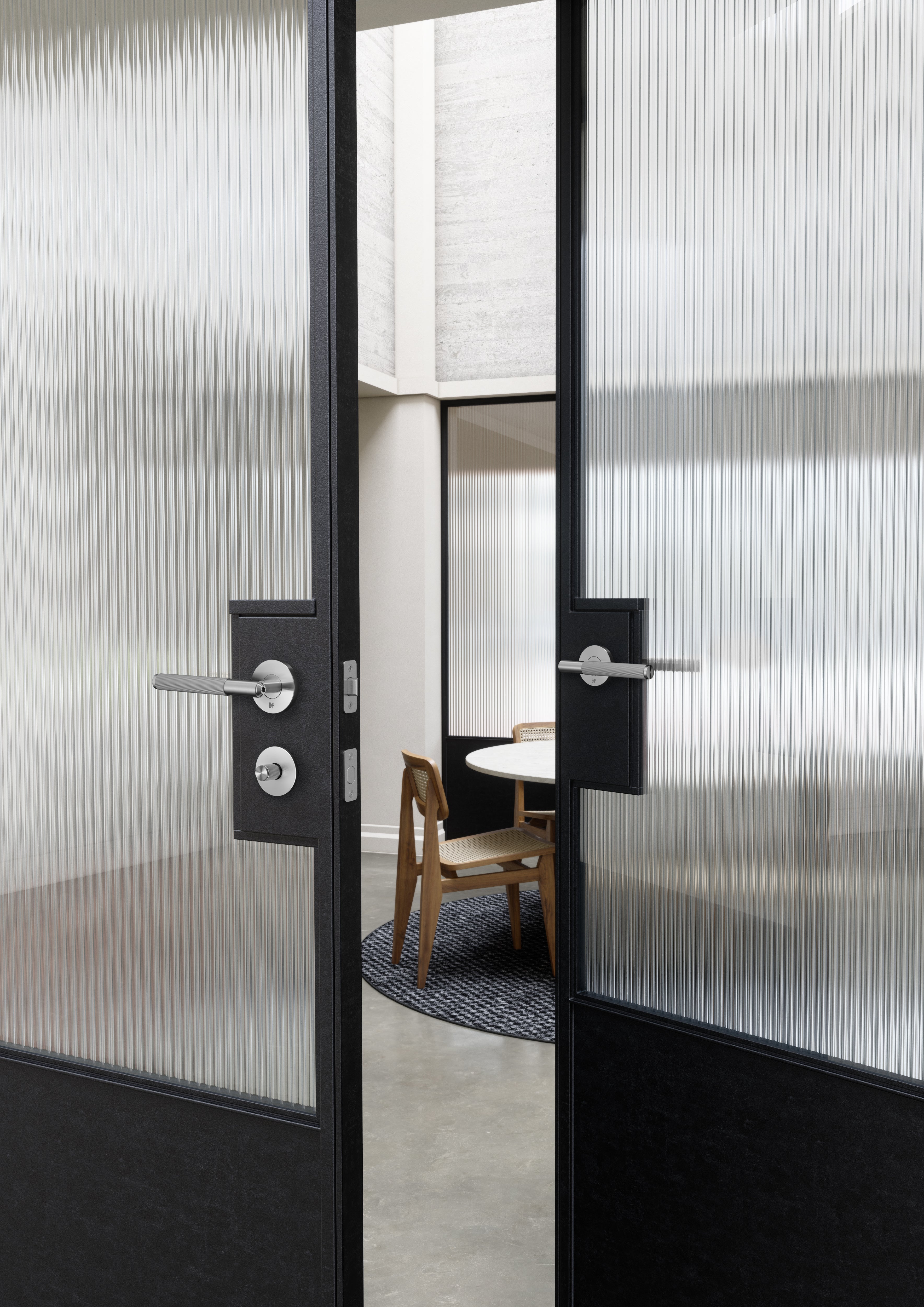 Vriderlås i rustfri stål og i eksklusivt design med linjeret mønster. Her ses vridelåsen monteret på en dør sammen med det matchende dørhåndtag også fra Buster + Punch.
