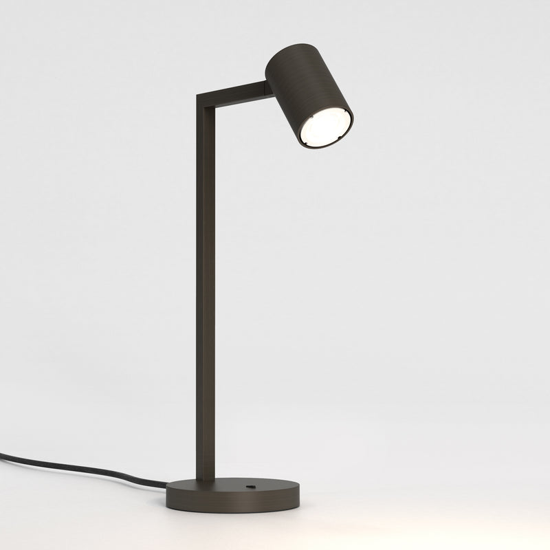Bronzefarvet bordlampe med justerbar hoved. Lampen har et enkelt design med firkantede linjer/vinkler.