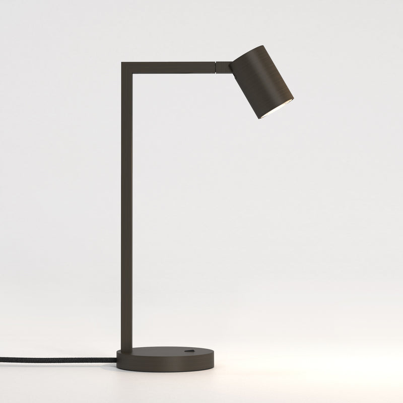 Bronzefarvet bordlampe med justerbar hoved. Lampen har et enkelt design med firkantede linjer/vinkler.