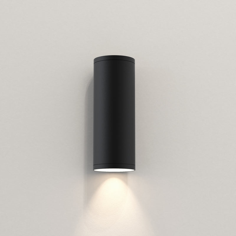Udendørslampe fra astro i sort med et rundt og aflangt design og med nedadgående kegleformet lys.