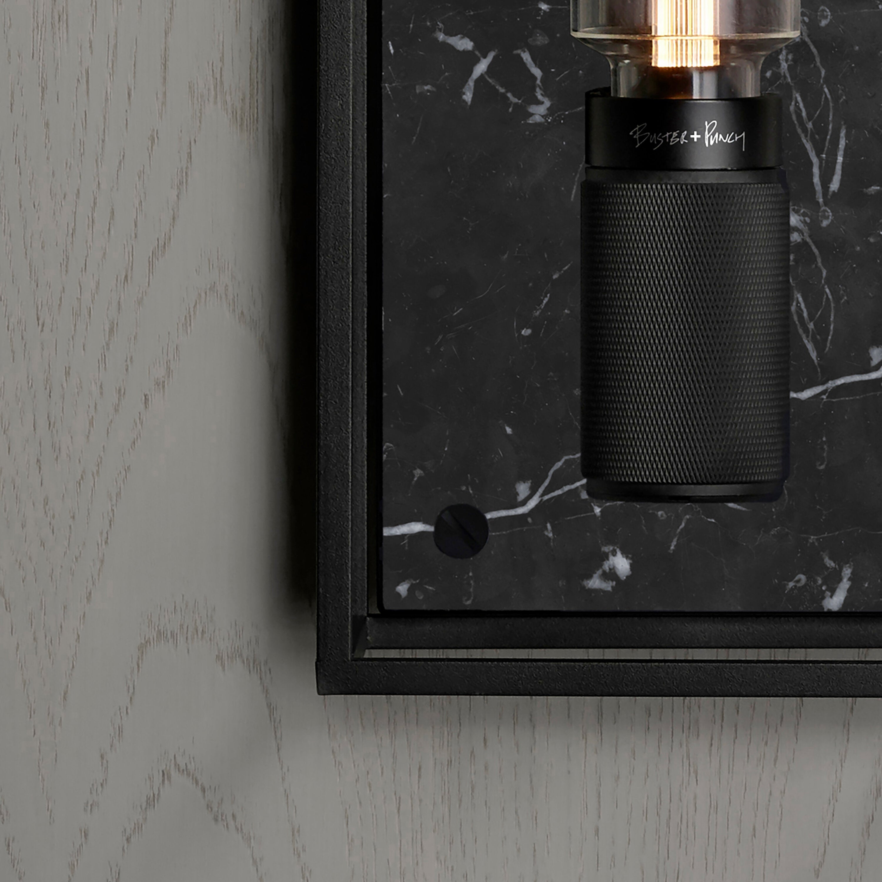 Buster and Punch caged wall lamp large i sort metal med bagplade i sort marmor.