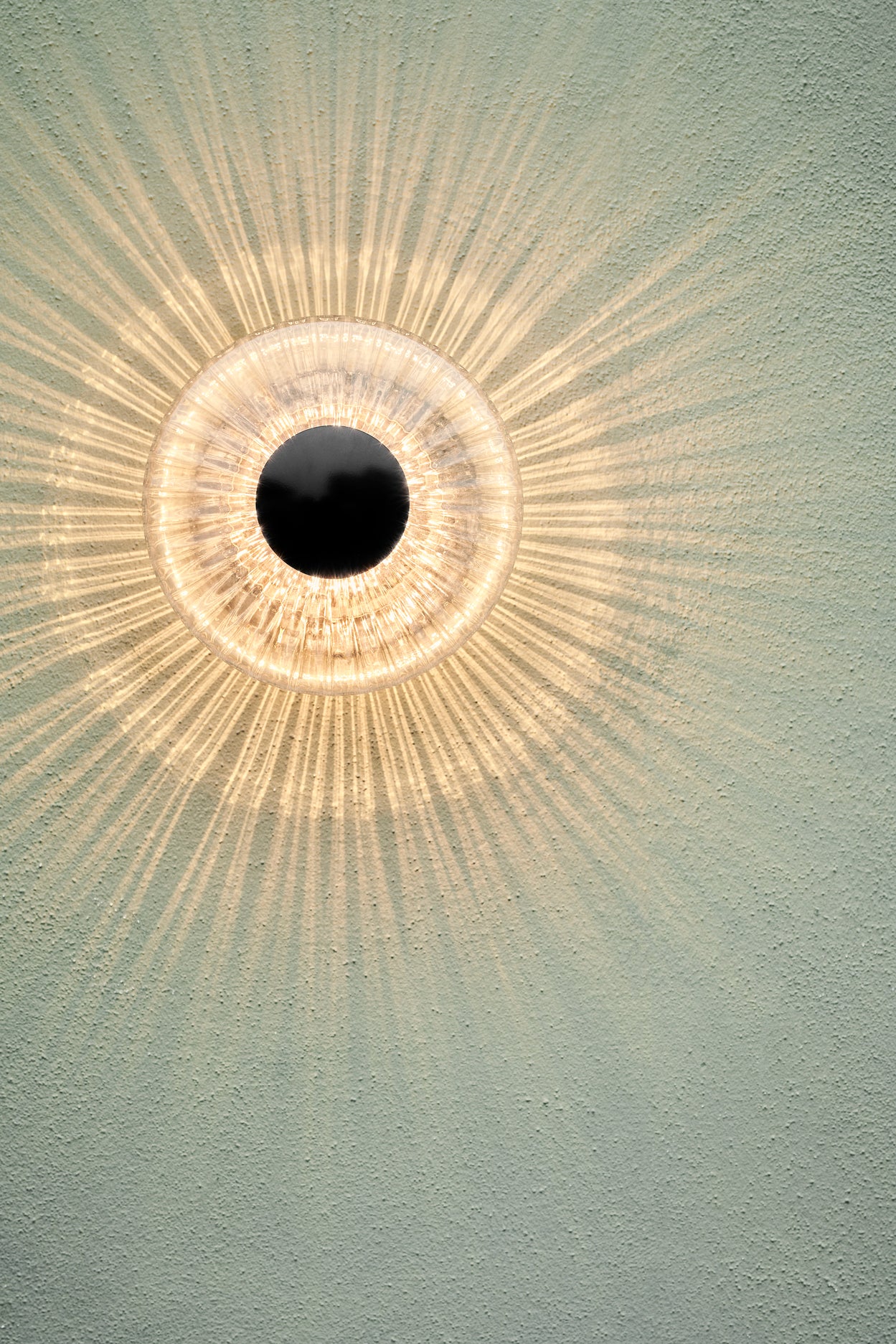 Rund udendørs væglampe af klart klart glas, på lys pudset mur