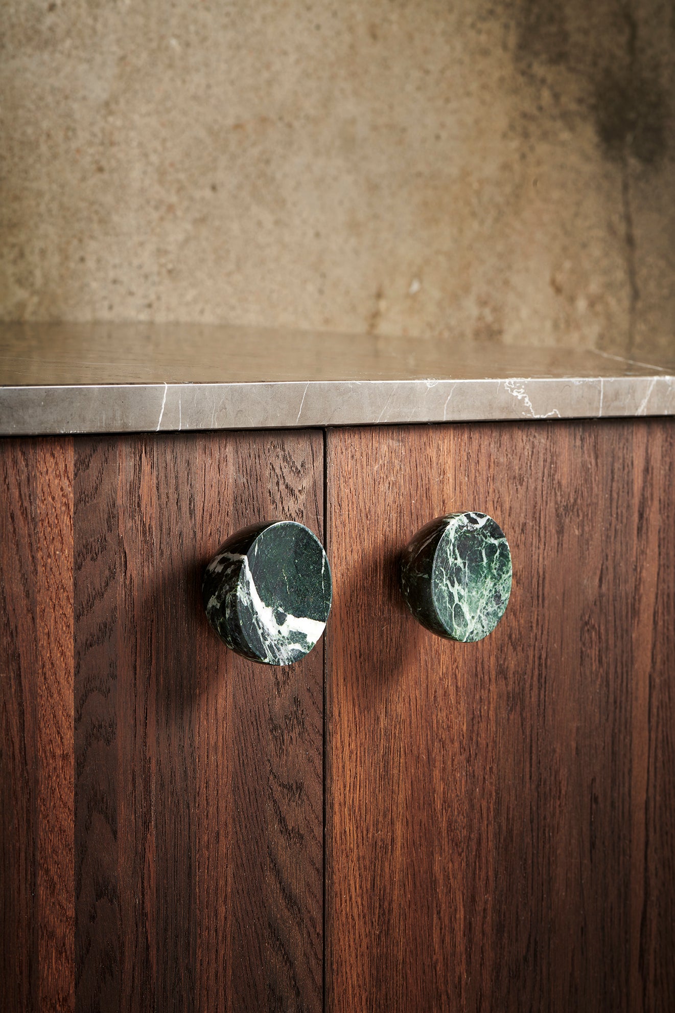 Rund konisk møbelknop i en dyb grøn marmor med hvide aftegninger. Her ses to stk. monteret på træfronter. 