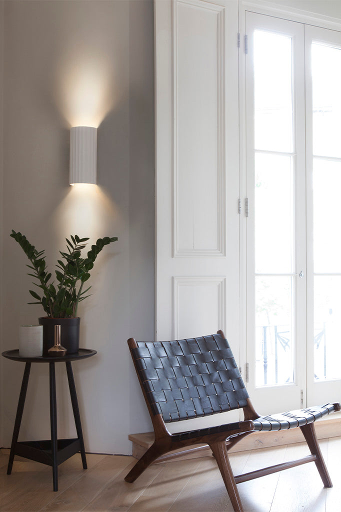 Elegant hvid væglampe med buede nedadgående linjer. Lampen har både opadvendt og nedadvendt lys.