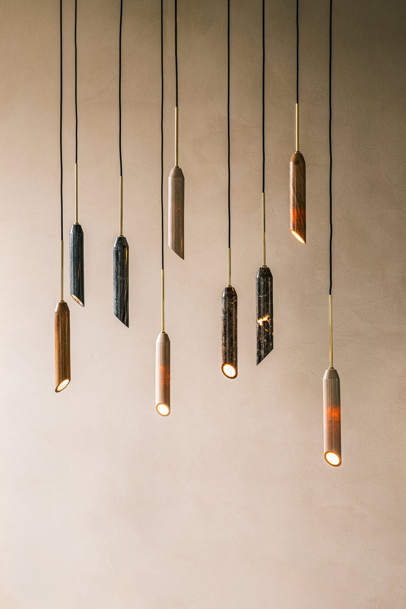 Pendel lampe i hvid marmor med diagonalt snit og med guldfarvet detaljer. Lampen har en sort stofledning.