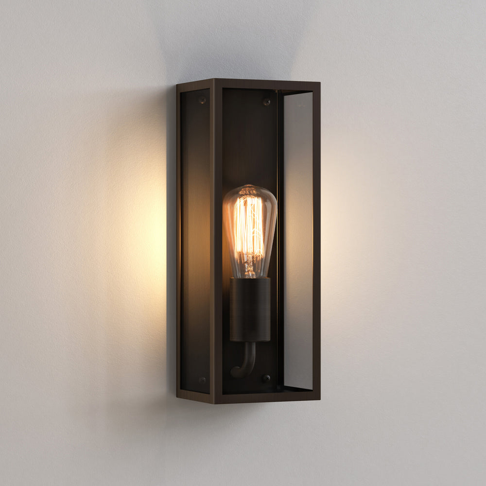 Aflang firkantet udendørslampe med bronzefarvet stålramme og glassider. Fremvist med en "glødepære".