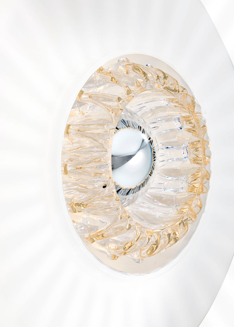 Rund væglampe i opal plisseret glas, som skaber et lysspil på væggen. 