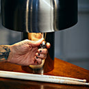 Eksklusiv og rå bordlampe i børstet rustfri. Bordlampen tændes via det lille dødningehoved vedhæng.