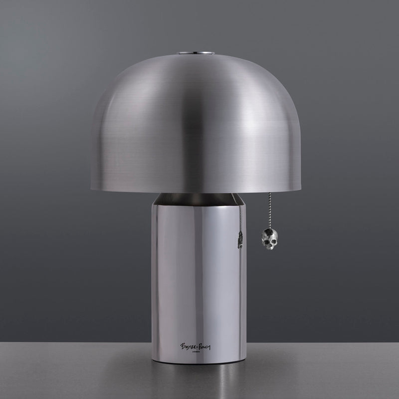 Eksklusiv og rå bordlampe i børstet rustfri. Bordlampen tændes via det lille dødningehoved vedhæng.