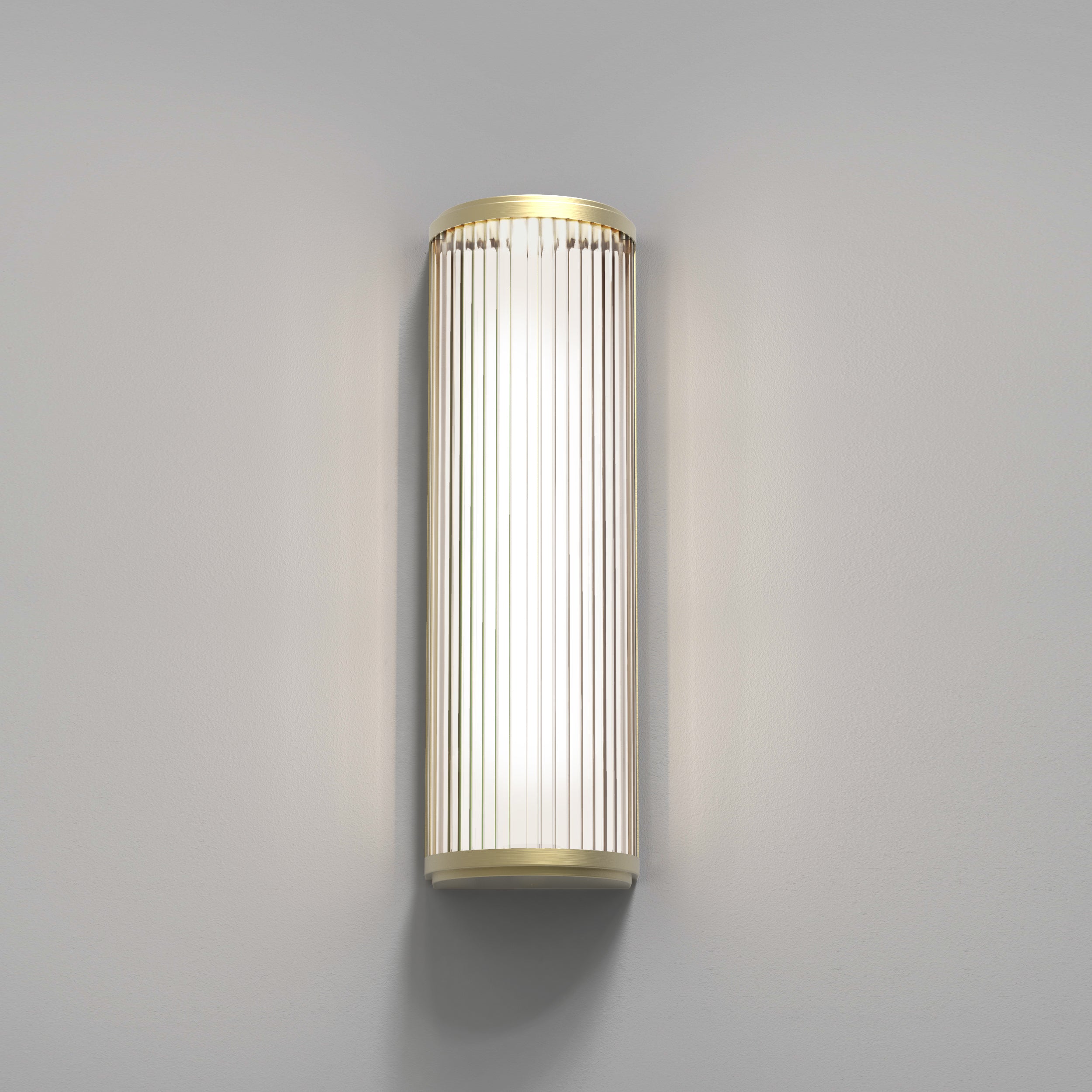 Aflang væglampe med top, bund og bagside i guldfarvet stål samt en buet glasskærm med linjer.